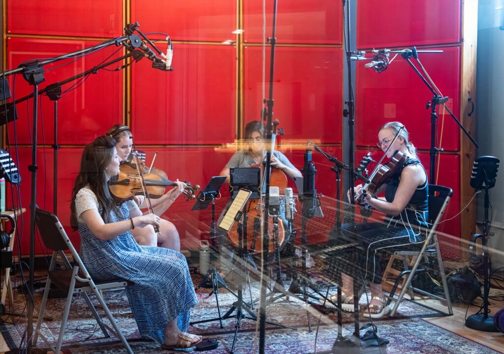 ATLYS recording in a red-walled studio surrounded by microphones